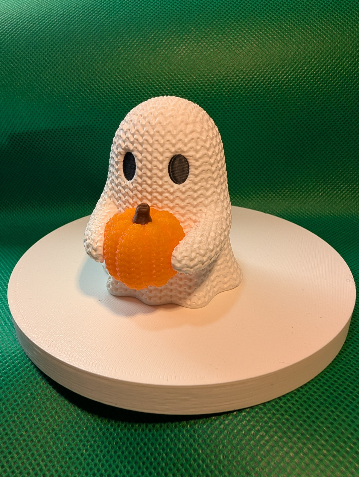 Knitted-style ghost holding a pumpkin, angled view