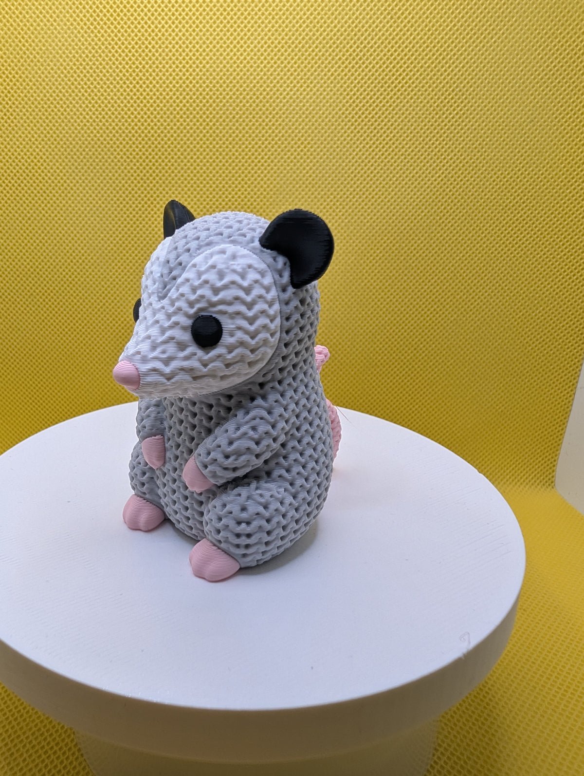 Angled view of grey and white opossum figurine