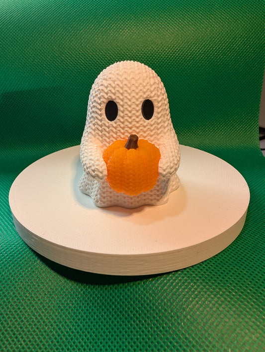 Knitted-style white ghost holding an orange pumpkin, front view