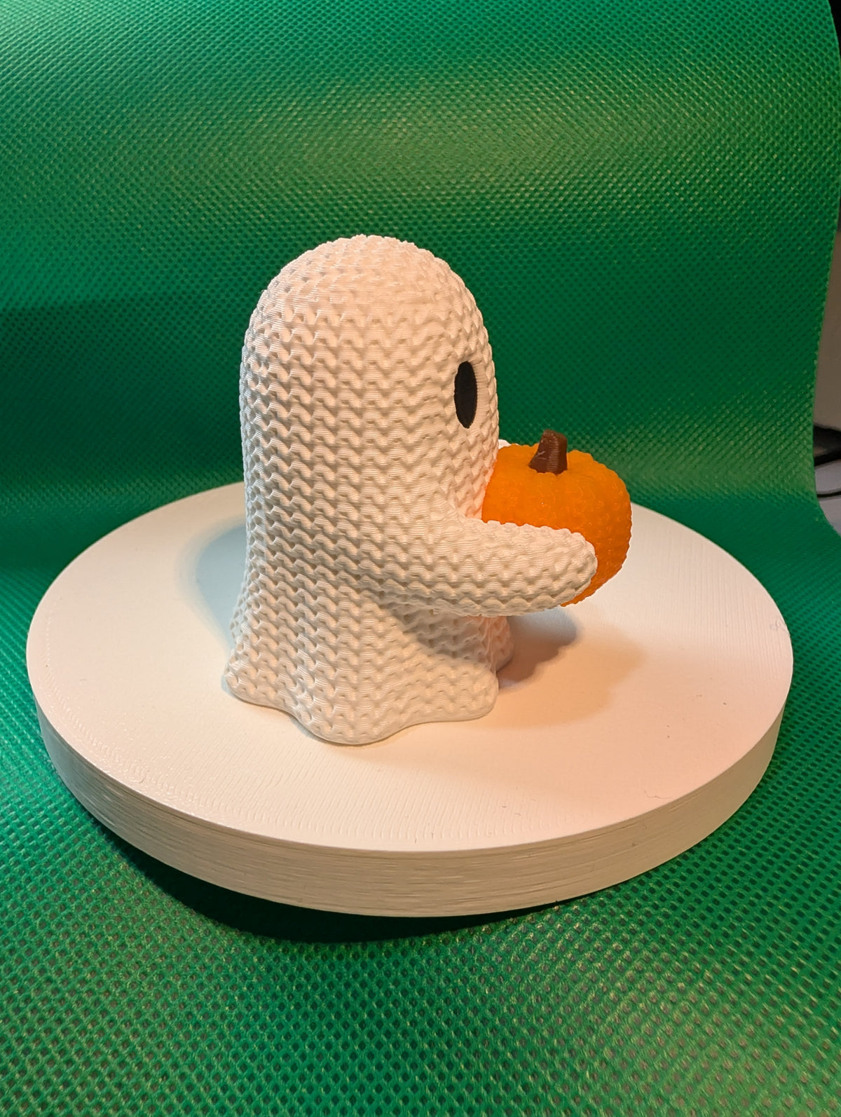 Knitted-style ghost holding a pumpkin, side view