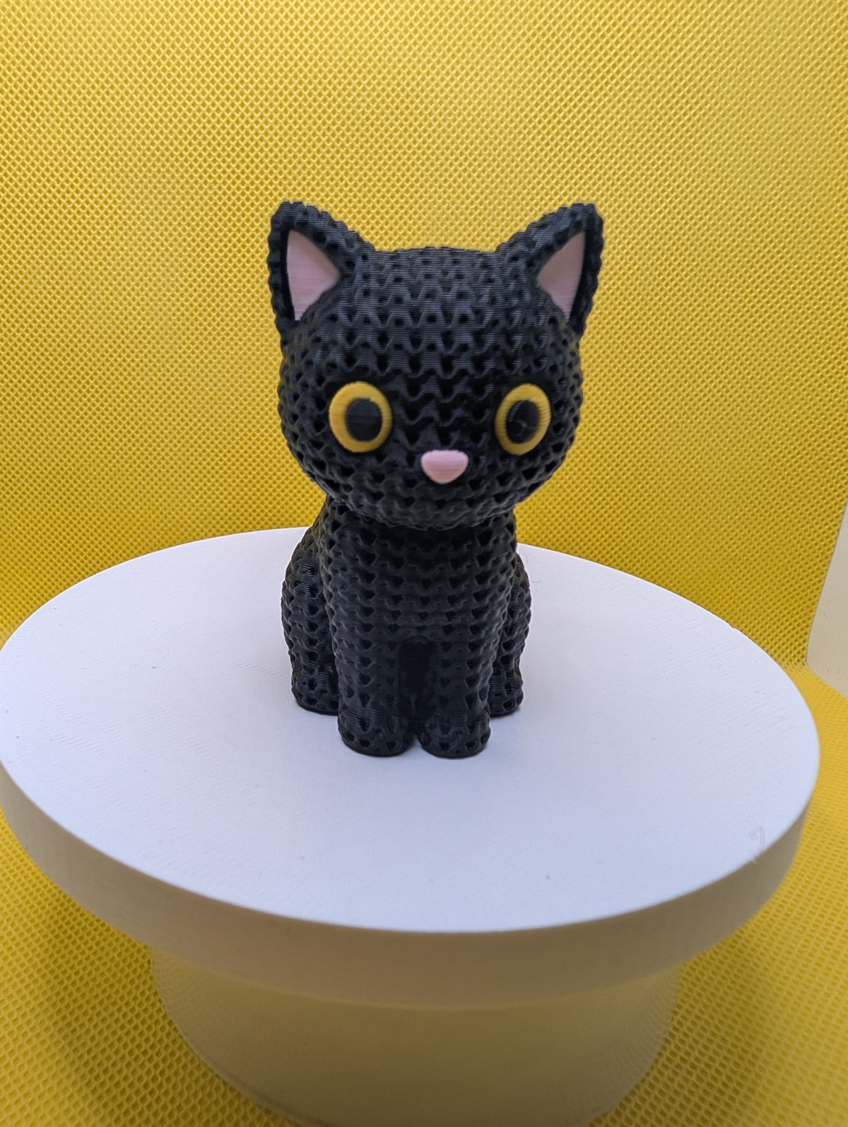 Front view of knitted-style black cat with yellow eyes and pink nose